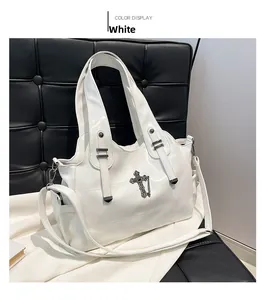 Dettaglio della borsa tote bianca in pelle con ciondolo a croce vintage su sedia nera