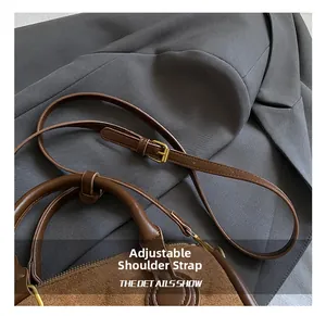 Detail eines verstellbaren Schultergurts mit goldener Schnalle an brauner Wildledertasche