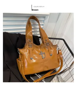 Dettaglio della borsa tote in pelle lucida marrone con ciondolo a croce e catena