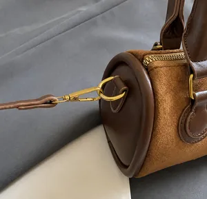 Nahaufnahme des goldenen Metallhakens an der braunen Wildleder-Zylindertasche