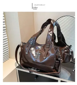 Dettaglio della borsa tote color caffè con ciondolo a croce vintage e finitura lucida