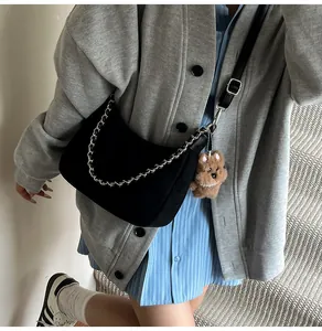 Detailansicht einer schwarzen Suede-Hobotasche mit Silberkette und Plüschbär