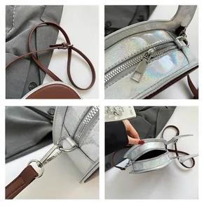 Dettaglio borsa laser argento con ganci metallici, cerniera e materiale olografico