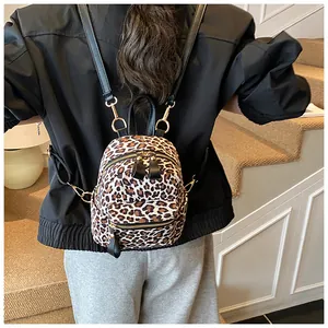 Detailed macro of leopard print mini backpack with golden metal zippers and black leather trim