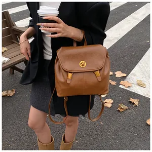 Dettaglio dello zaino vintage in pelle marrone con chiusura dorata rotonda e patta