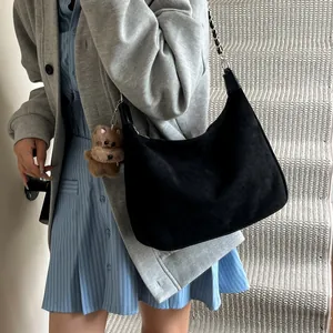 Schwarze Wildleder Schultertasche mit silberner Kette und Bärenanhänger am Modell
