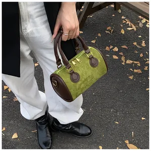 Detaillierte Draufsicht einer grünen Wildledertasche mit braunen Griffen und Goldreißverschluss