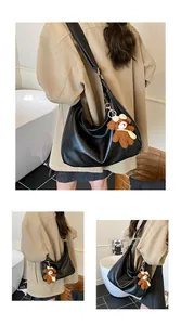 Détail du sac hobo en similicuir noir avec un charmant ours en peluche et bandoulière
