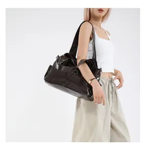 Dettaglio di una grande borsa tote in pelle verniciata marrone scuro su modella per stile