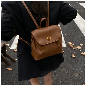 Dettaglio dello zaino vintage in pelle marrone con chiusura a rotazione e fibbie dorate