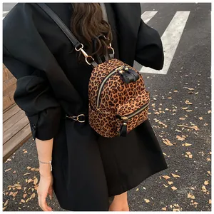 Outdoor street shot of a mini leopard print backpack with gold zippers on black coat