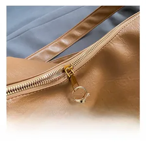 Détails du sac fourre-tout marron avec fermeture éclair dorée et porte-clés ours en peluche