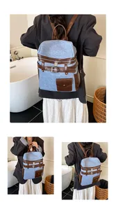 Detail of light blue denim backpack with brown leather straps and metal buckle accents