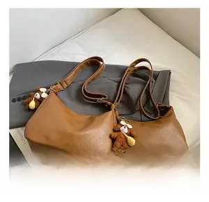 Détail d'un sac cabas vintage marron avec charm ours en peluche sur un tissu doux