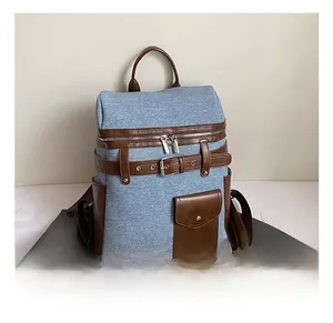 Detail of blue denim and brown leather backpack with metal buckles and side pockets