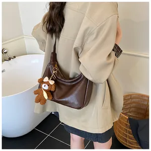 Détail du sac hobo en similicuir marron foncé avec un joli pendentif ours en peluche