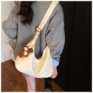 Détail du sac hobo crème avec large bandoulière et charmant pendentif ours en peluche