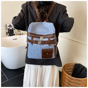 Detail of light blue denim backpack with brown leather straps worn by a model