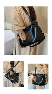 Detail van de zwarte leren tote bag met verticale stiksels en bruine beer hanger