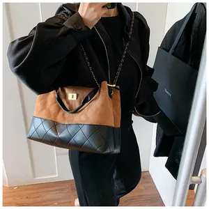 Detail of suede and quilted leather patchwork tote bag with gold metallic twist lock