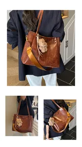 Detail van vintage bruine shopper met gele riem en pluche berenhangertje