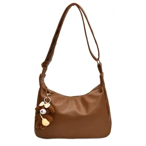 Sac hobo vintage en similicuir marron avec breloque ours en peluche sur fond blanc