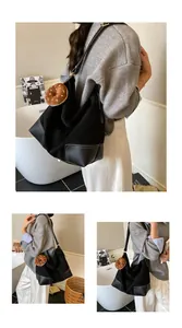 Detail van de zwarte hobo-tas met contraststiksel en donut pluche hanger