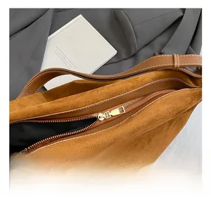 Detail van de gouden rits en bruin suède textuur op een grote tote tas voor dames