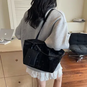 Minimalist black tote bag with long strap and small card pouch shown on model
