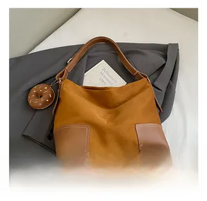 Detailweergave van grote suède shopper met lederen hoeken en donutvormige hanger