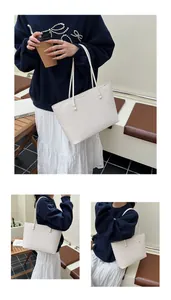 Detail showing white woven tote bag with herringbone texture and long shoulder straps