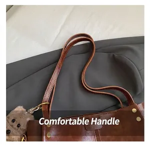 Detail van retro bruine lederen shopper met gouden klinknagels en een schattige pluche hanger