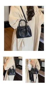 Detailed view of black woven texture leather handbag with adjustable crossbody strap