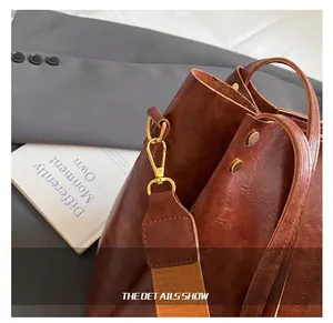 Detail van de leren shopper met gouden karabijnhaak en gestreepte geweven riem