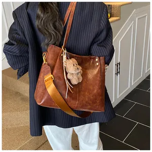 Bruine vintage leren shopper met oranje geweven schouderriem en pluche beer-accessoire