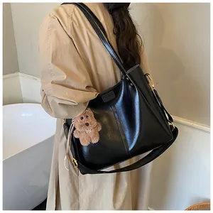 Detailoverzicht van grote zwarte leren shopper met pluchen beer en gouden hardware
