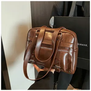 Detail of dark brown faux leather pillow bag with silver buckles and zipper pockets