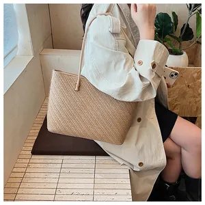Detail of woven wheat pattern tote bag with leather strap on a model shoulder