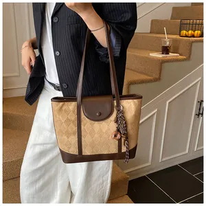 Detail of khaki quilted tote bag with brown leather trim and silk scarf donut charm