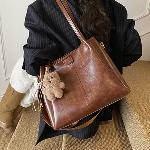 Grote retro bruine tote bag van kunstleer met schouderbanden en een berenbedeltje