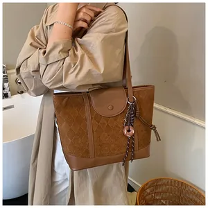 Detail of brown quilted tote bag with suede texture and elegant tassel charm