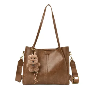 Bruine kunstleren shopper met brede geweven schouderband en een schattige teddybeerhanger