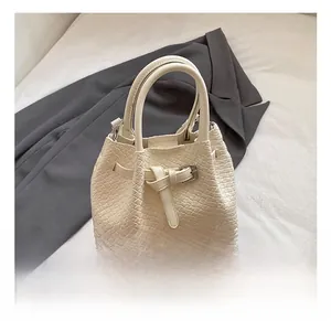 Detailed view of cream white woven handbag featuring elegant belt buckle and dual handles