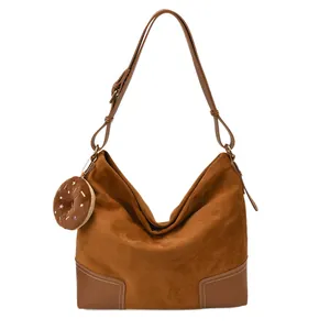 Bruine suède hobo tas met verstelbare riem en decoratieve pluche bedel vooraanzicht