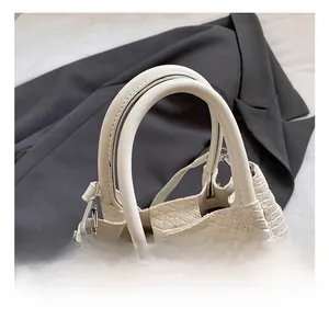 Detail shot of the cream-colored woven texture and smooth dual handles on the handbag