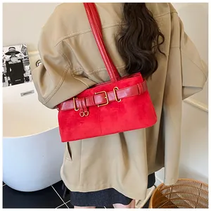Detalle de bolso bandolera de ante rojo con hebillas doradas llevado por una modelo