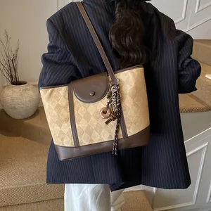 Retro plaid tote bag with brown leather trim and quilted texture shown on shoulder