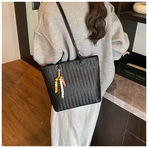 Détail du cabas en cuir PU tressé noir avec pompon en perles colorées et bandoulière