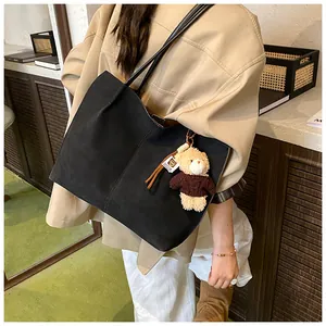 Detail der schwarzen matten Shopper Tasche mit dünnen Trägern und Plüschbär-Anhänger