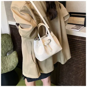 Detailed view of a white woven shoulder bag with bow knot and adjustable leather strap